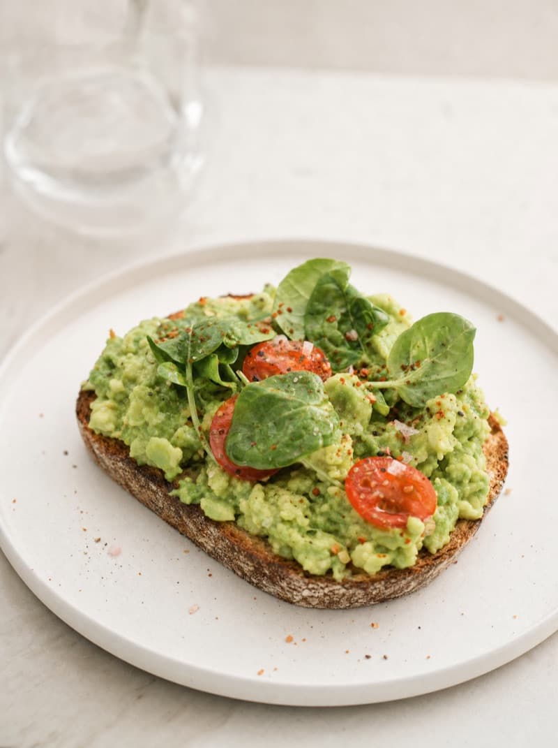 Smashed avocado on toast with cherry tomatoes and rocket